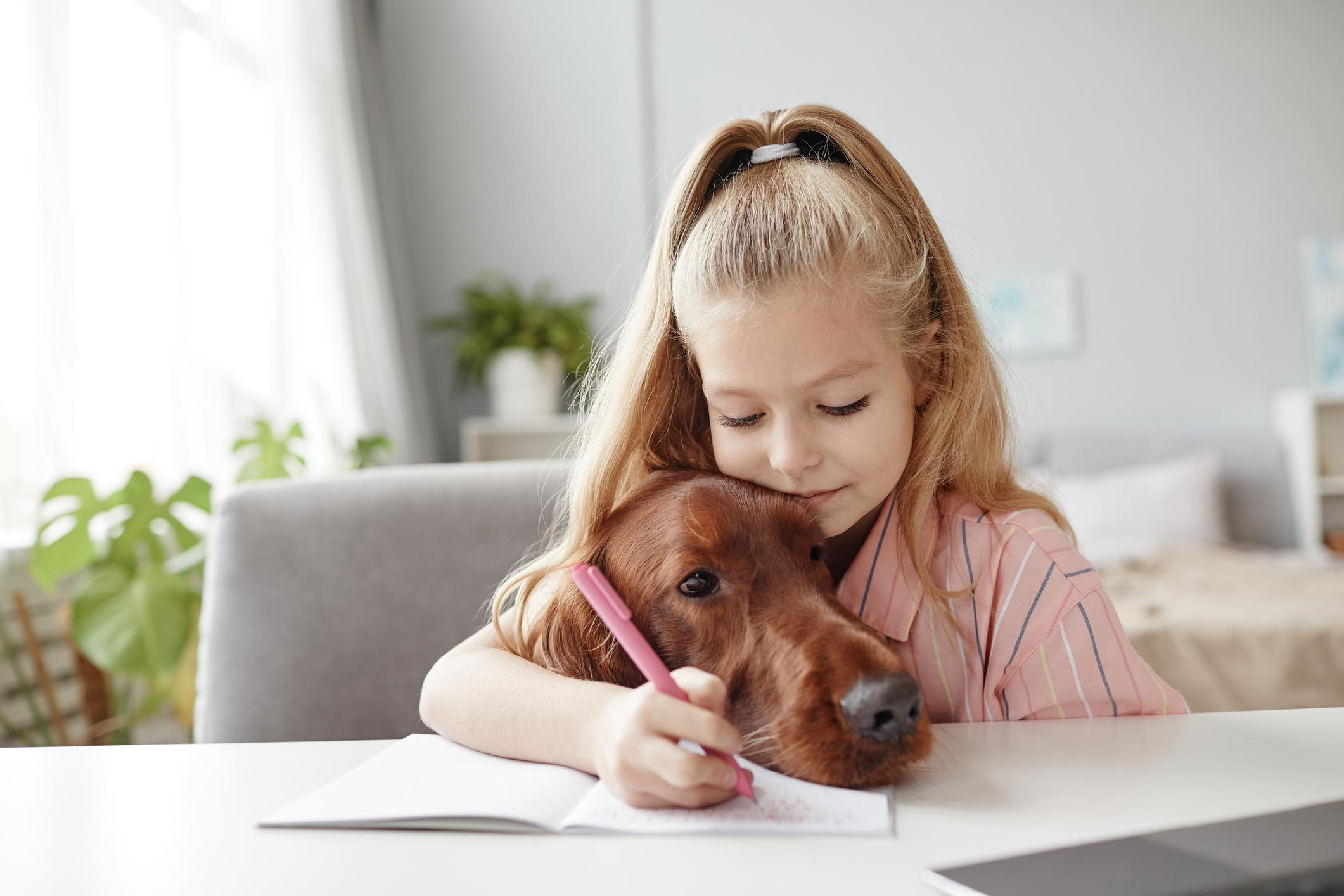 Little Girl Embracing Dog doing Schoolwork