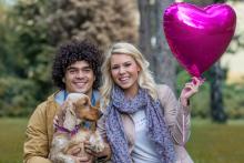 man and woman couple holding a balloon with their dog