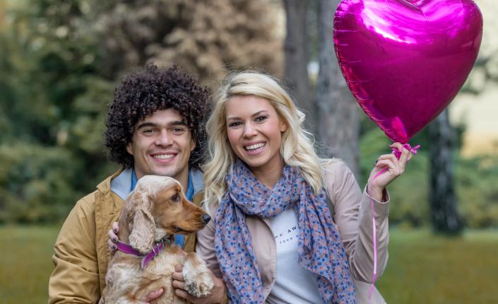 man and woman couple holding a balloon with their dog